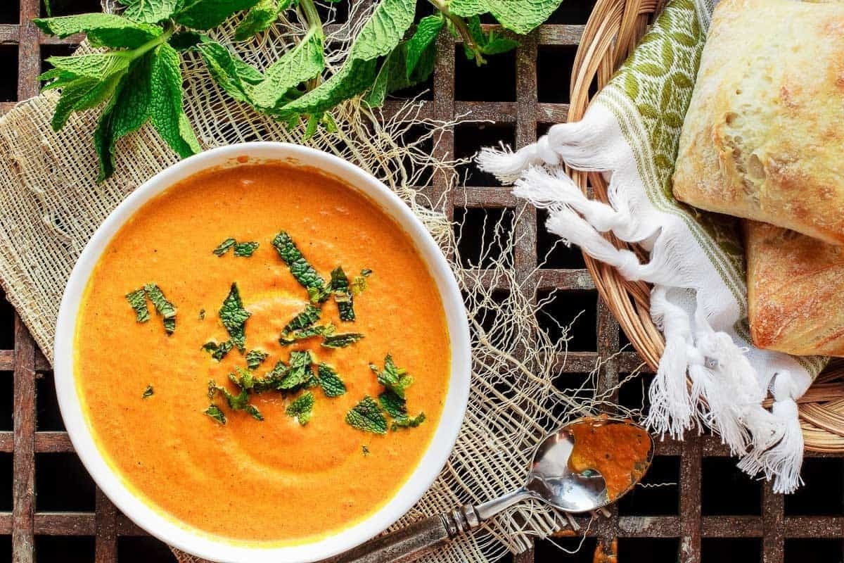 roasted-carrot-ginger-soup Bowl of Roasted Carrot Soup garnished with mint leaves