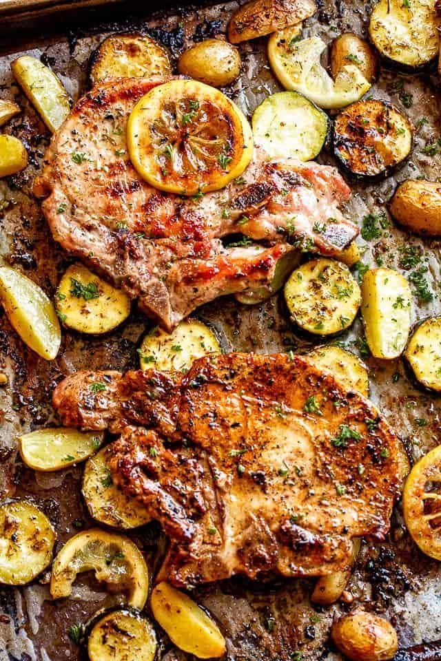Lemon garlic baked pork chops with squash and potatoes on a sheet pan.