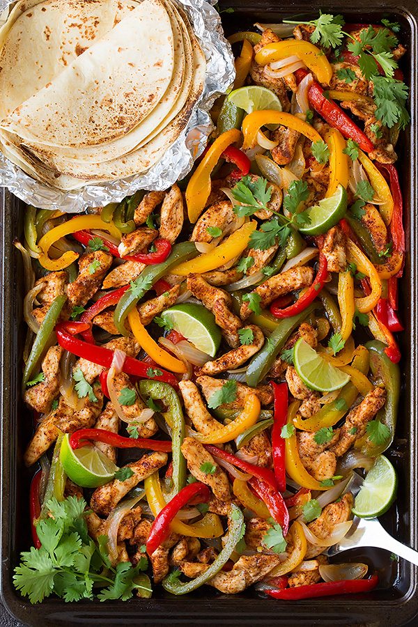 Chicken fajitas with well-seasoned chicken breast, onions, and peppers cooked in a sheet pan.
