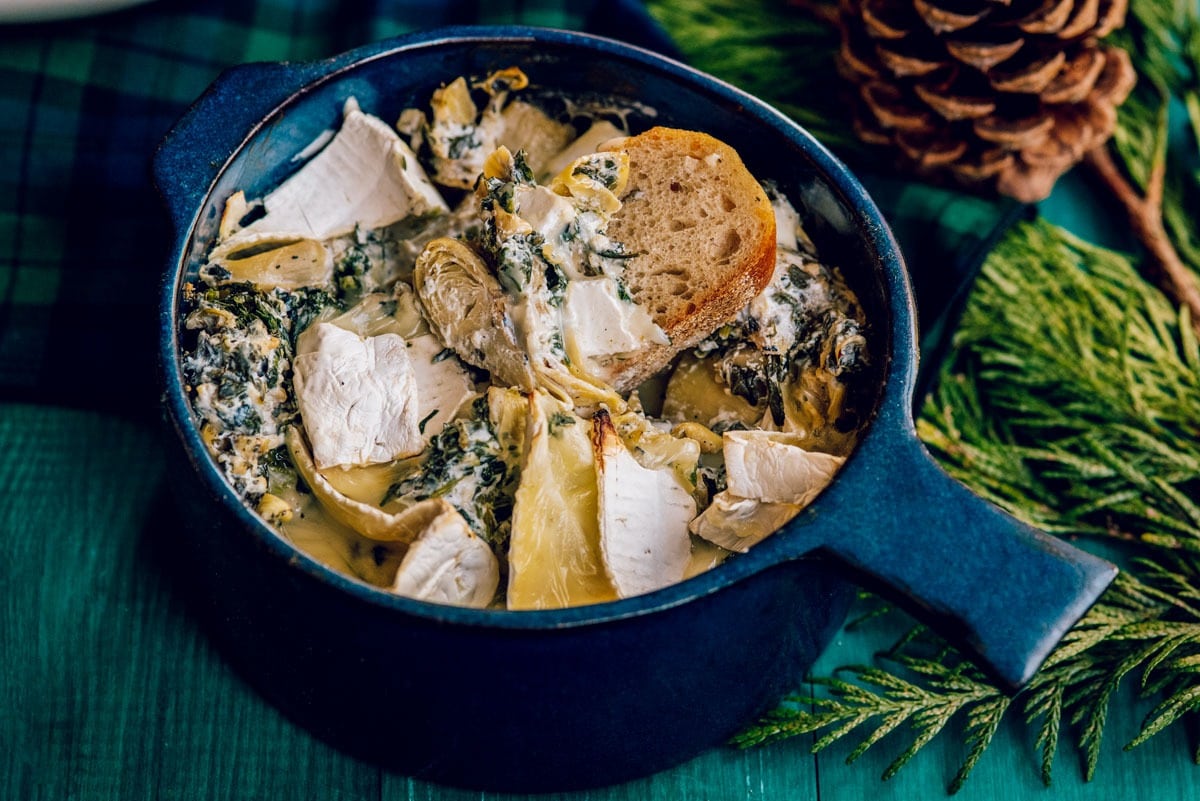Spinach artichoke dip with brie on a pot.