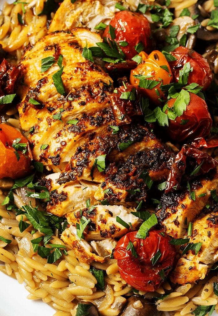 baked-sun-dried-tomato-chicken Baked chicken cooked with sun dried tomatoes topped on rice garnished with herbs and spices.