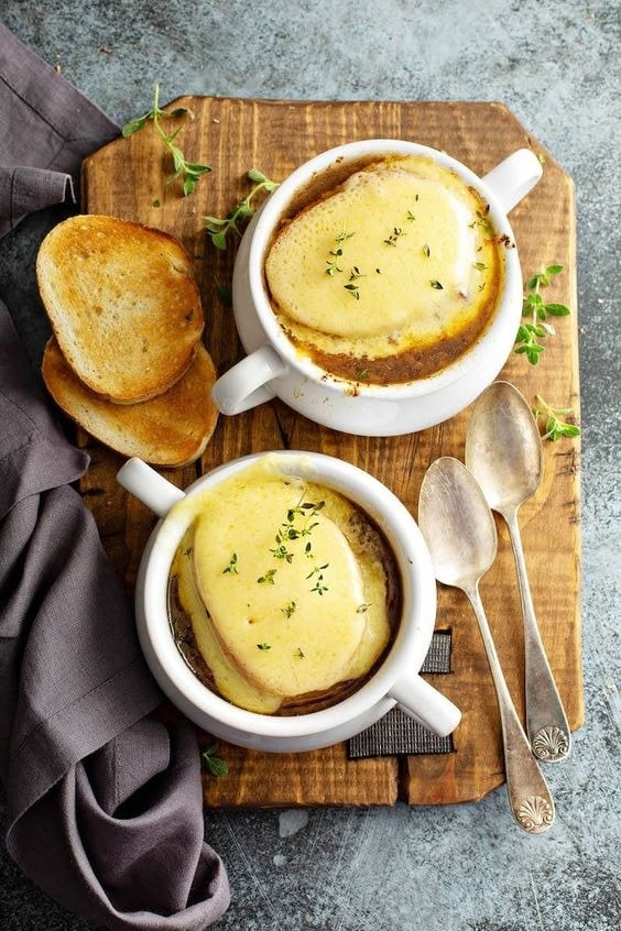 beef-and-barley-soup-1 Beef and barley soup topped with melted cheese on a white mug with toasted bread.