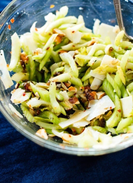 celery-salad-with-dates-almonds Celery salad with dates, almonds and parmesan in a glass bowl.