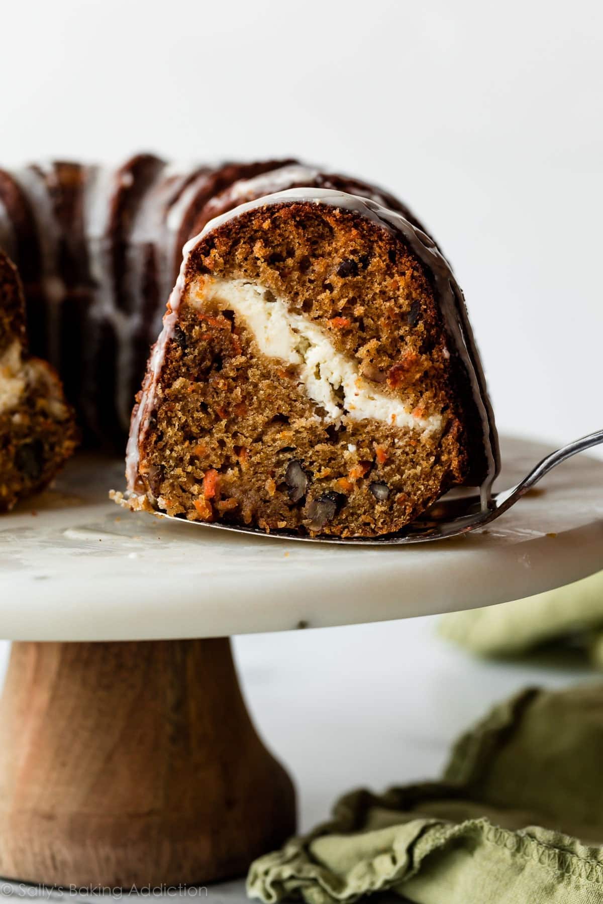 cheesecake-swirl-carrot-cake-bundt-cake Pie ladle picking a slice of a carrot Bundt cake with cheesecake filling.