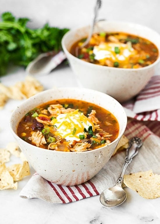 chicken-enchilada-soup Chicken enchilada soup in bowls top with cream and grated cheese.