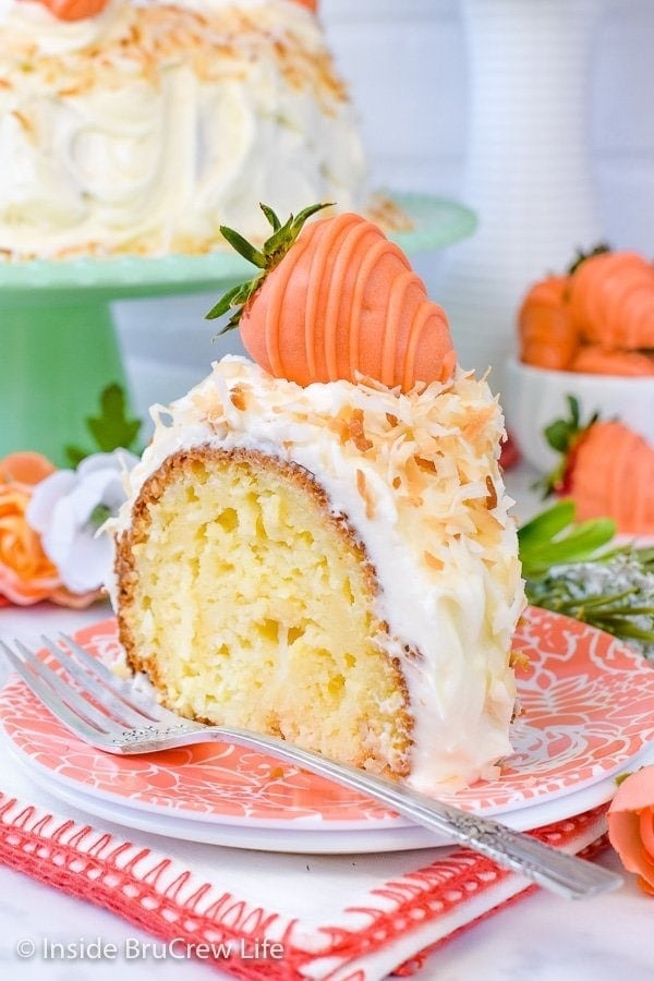 coconut-cream-bundt-cake Slice of Bundt cake coated with coconut cream and topped with a strawberry shaped frosting.