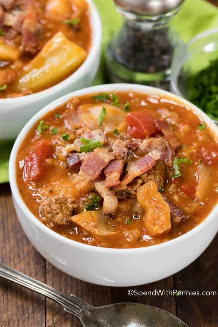 crock-pot-cabbage-roll-soup Cabbage roll soup served in bowls topped with bacons strips and chopped leaves.