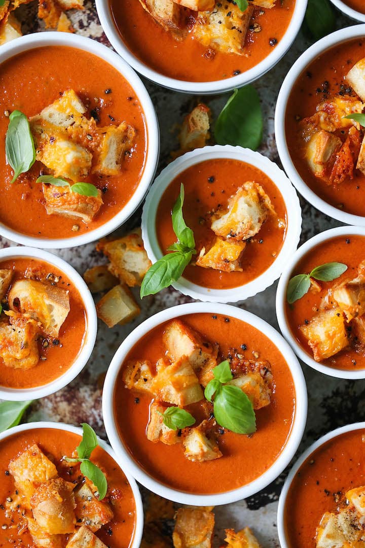 slow-cooker-tomato-basil-soup Tomato basil soup served in bowls topped with croutons and fresh basil leaves.