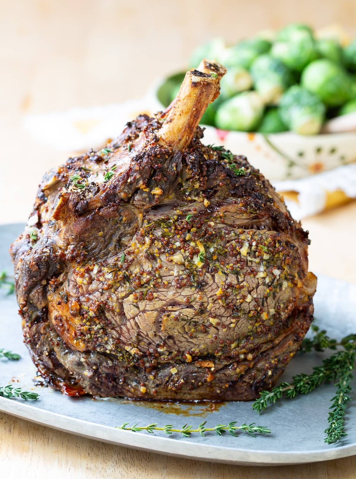 Roasted rib eye steak covered with spices and seasoning served upright on a plate.