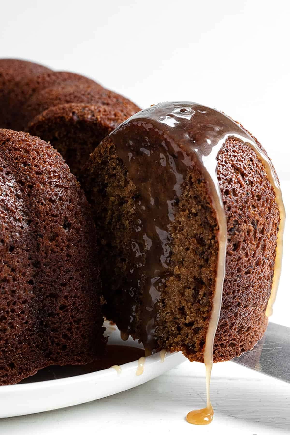 sticky-toffee-bundt-cake Cut of portion of a Bundt cake with dripping sugar glaze.