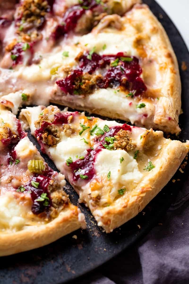 Sliced pizza topped cheese, turkey ,meat, cranberry sauce and chopped celery.