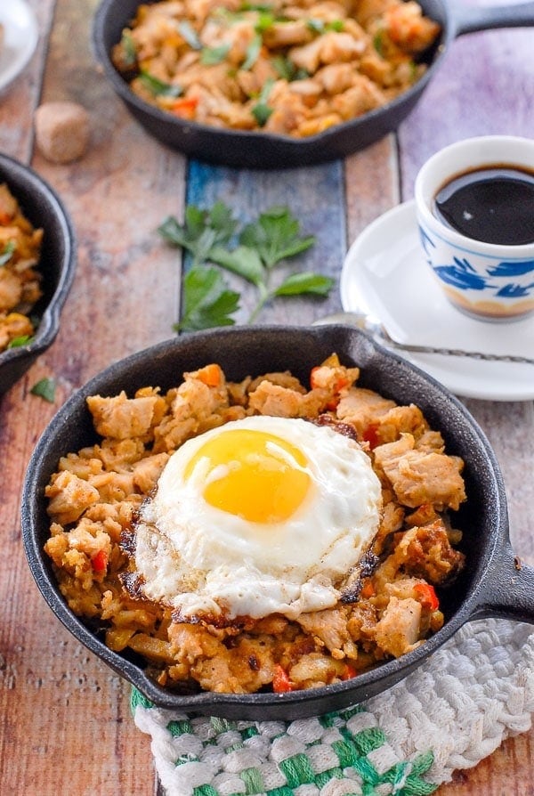 Turkey meat with stuffing topped with whole fried egg on a cast iron pan.