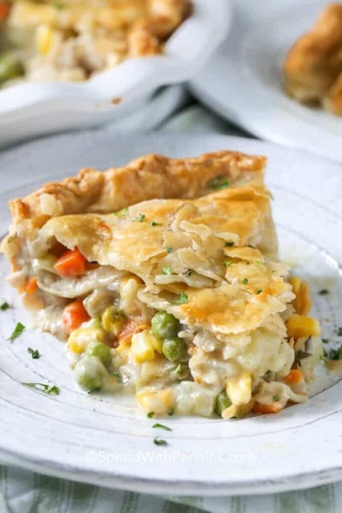 A slice of turkey pot pie with sauce, turkey, and veggies filling.
